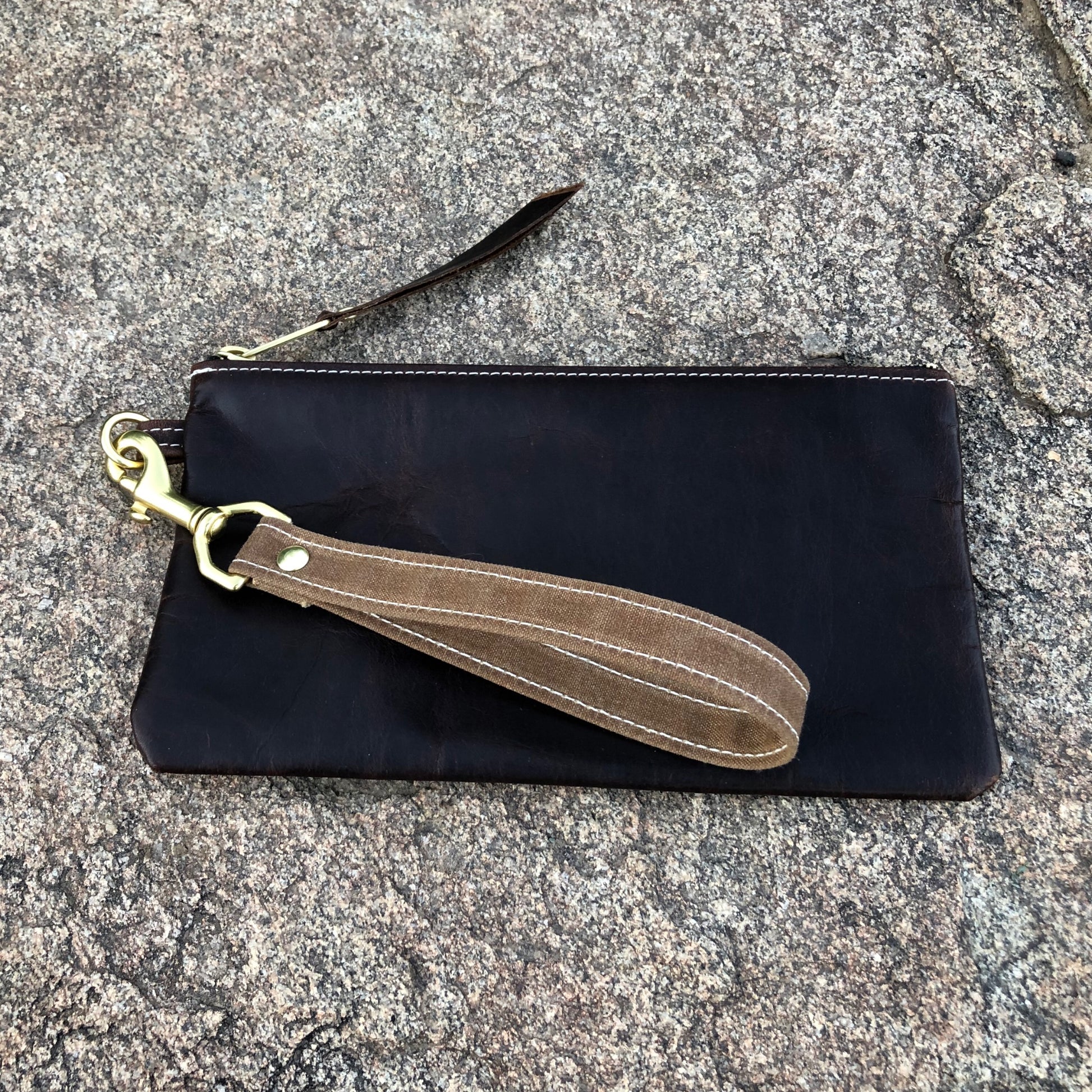 Pull-up leather wristlet wallet with a waxed canvas strap.