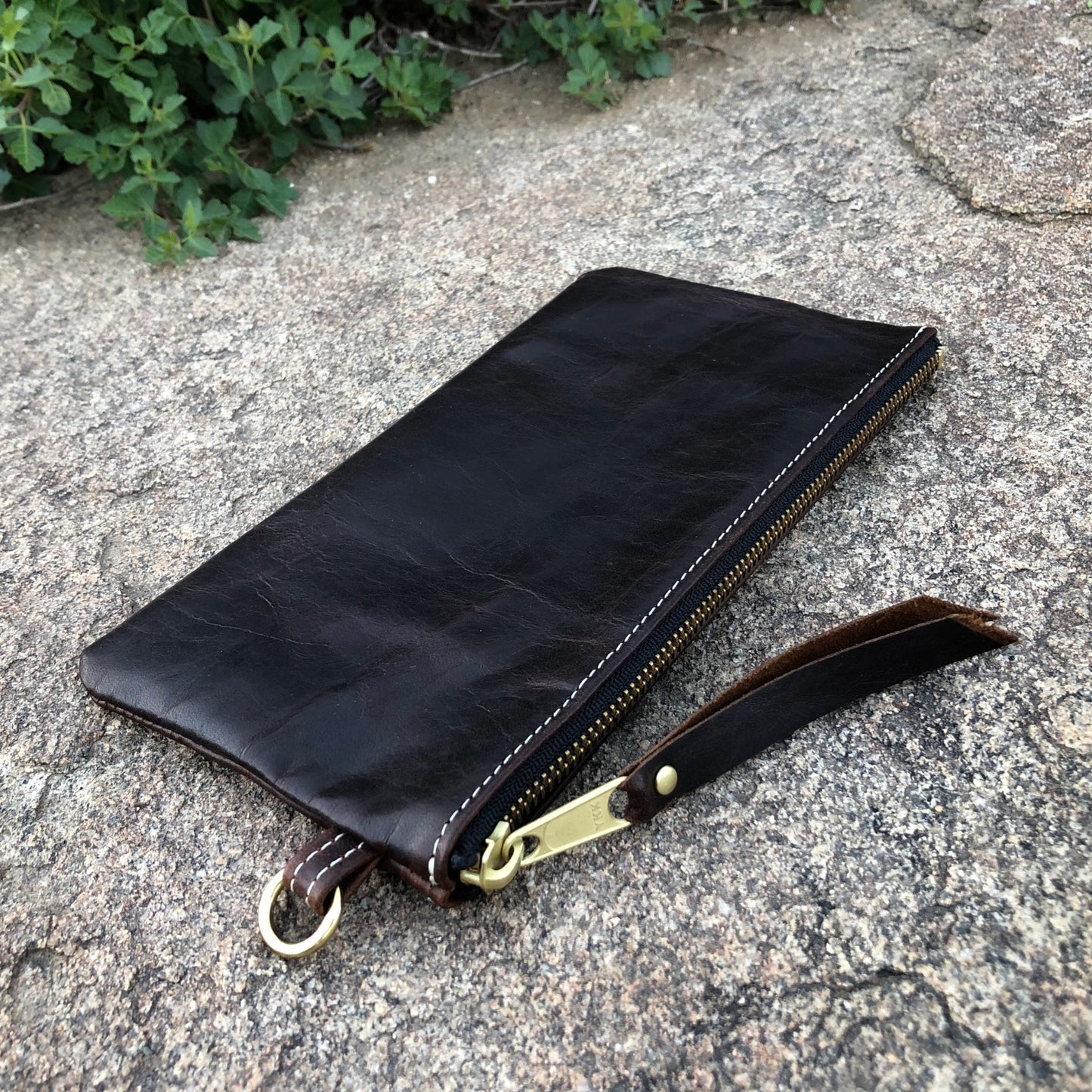 A dark brown zipper pouch handcrafted with luxury pull-up leather in a limited quantity.