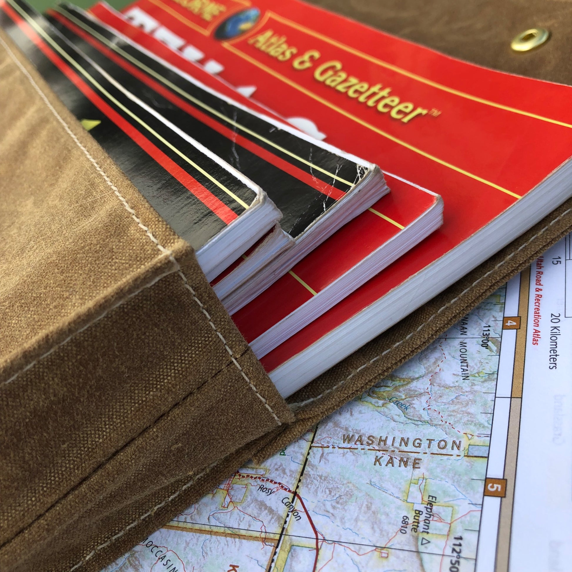 Brown waxed canvas map case for large format road atlases and recreation guides by benchmark maps. Handcrafted by Road dirt and pie